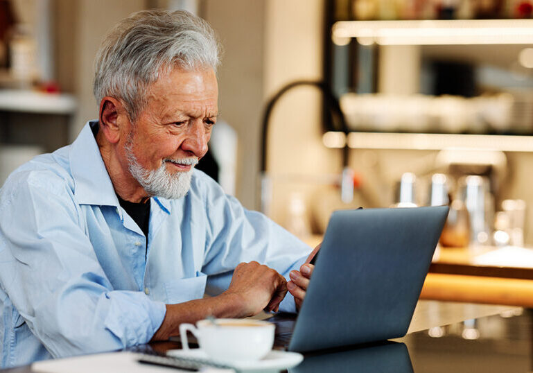 Retired U.S. expat smiling while researching Social Security benefits on a laptop over coffee, representing the planning challenges Americans abroad face with Social Security