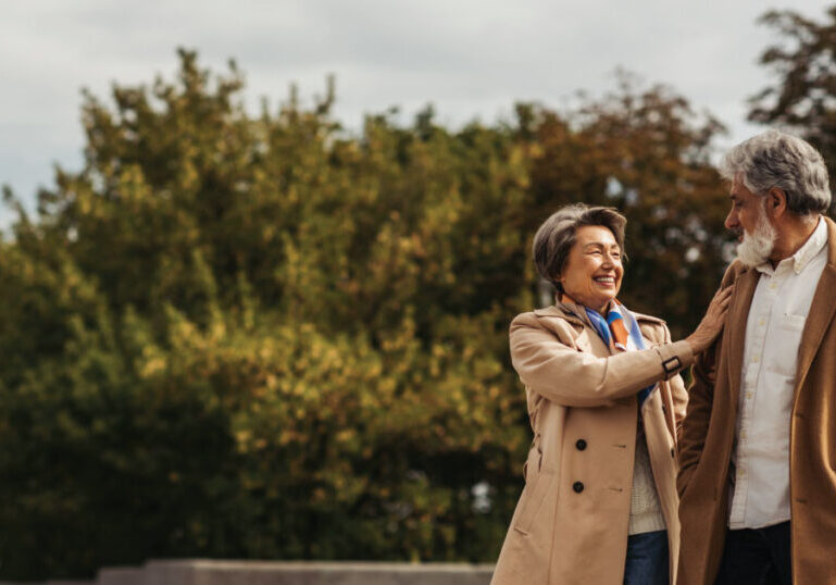 Senior woman walking with husband through park.