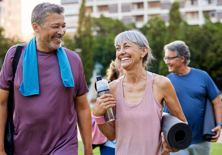 Smiling mature couple walking outdoors with workout gear, symbolizing mixed-status spouses coordinating cross-border financial planning and U.S. tax strategies for transferring appreciated assets