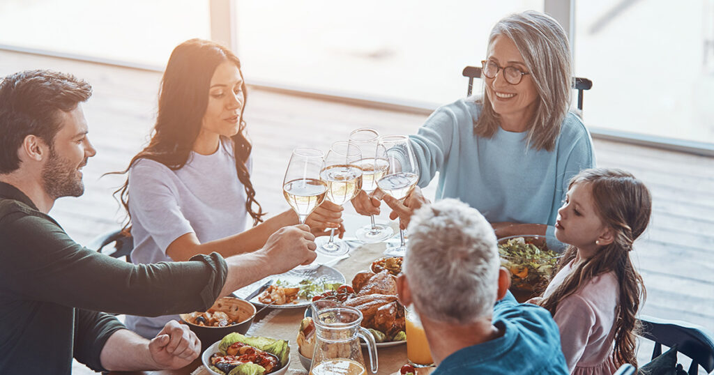 Multigenerational family toasting with wine glasses at a holiday dinner table, representing the integrated guidance family office advisory services provide to help preserve and transfer wealth across generations