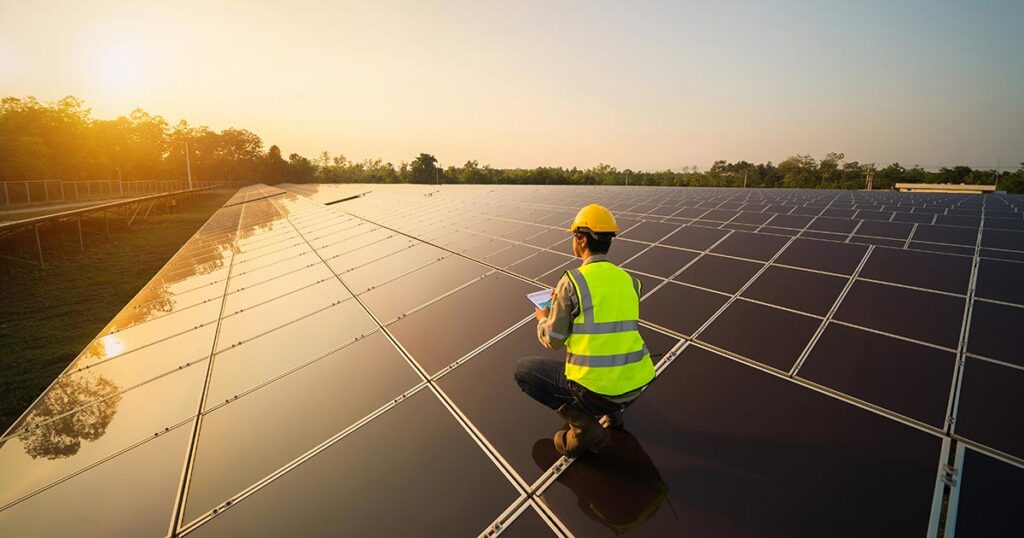 Impact investing professional evaluating a large solar energy project at sunrise, symbolizing sustainable finance and positive environmental change