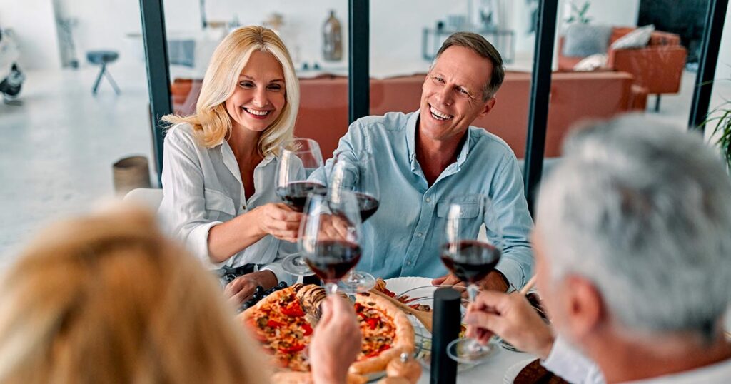 High-net-worth friends enjoying a celebratory dinner together, symbolizing the lifestyle supported by comprehensive wealth management and coordinated family office strategies