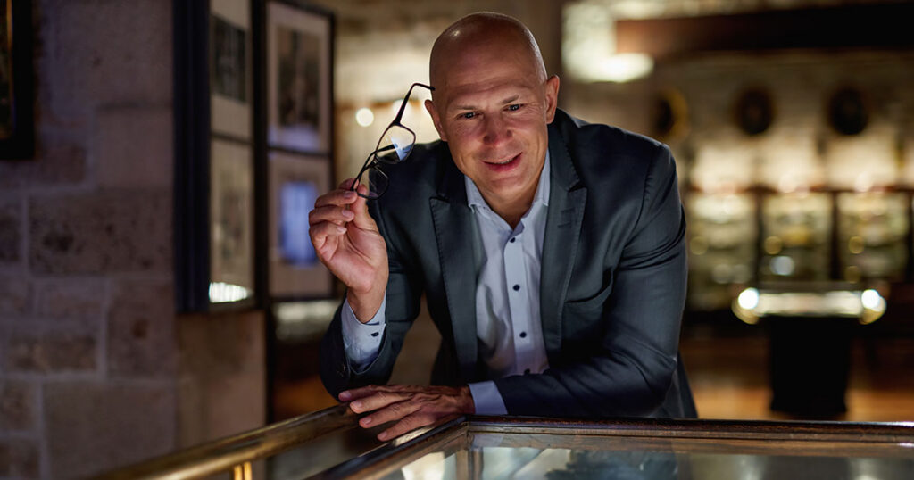 Ultra-high-net-worth individual thoughtfully reviewing a luxury asset collection, symbolizing strategic wealth management and legacy planning