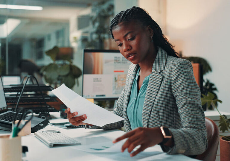 Black woman, documents and reading by computer in office for project, admin and review for proposal. Person, paperwork and pc for research, planning and feedback for perspective at creative agency.