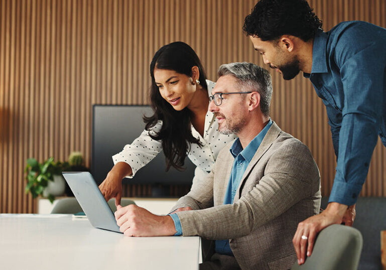 Strategic wealth advisors collaborating over a laptop to evaluate modern family office software solutions