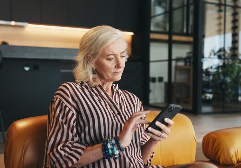 Woman carefully reviewing a message on her smartphone at home, illustrating personal vigilance and fraud prevention against financial crime and digital scams