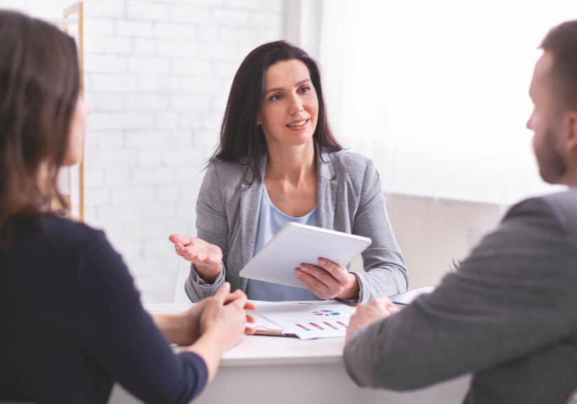 A young, professionally dressed woman talks to her divorcing clients
