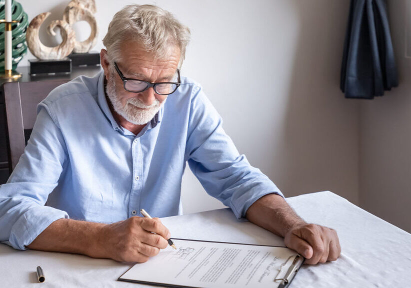Senior man examining and signing his will