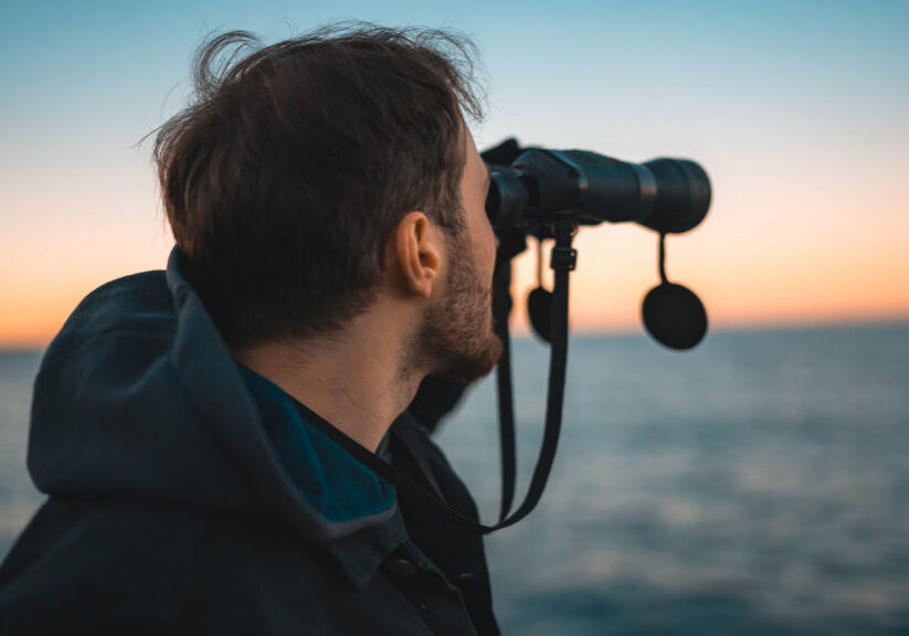 Man using binoculars to view the rough sea