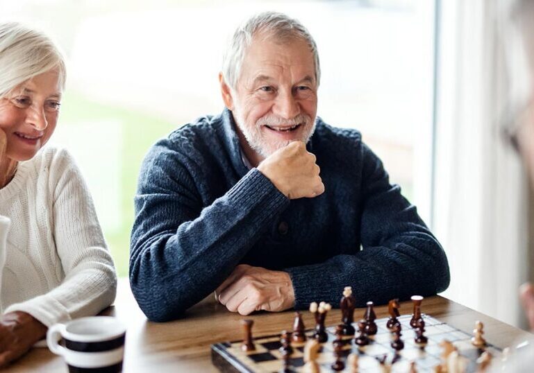 Ultra-high-net-worth family members in a thoughtful conversation over a chessboard, symbolizing the emotional and strategic decisions involved in managing significant family wealth.