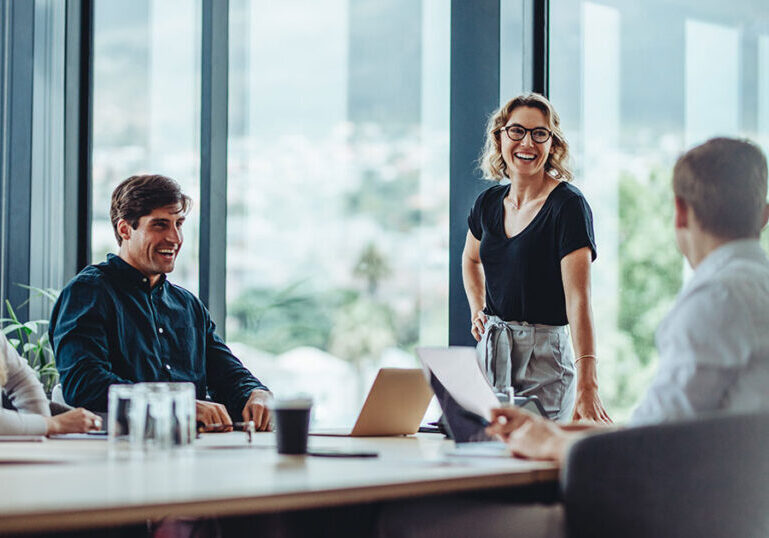 Group of professionals meeting around a conference table in a modern glass-walled boardroom, representing family office governance models and structured decision-making for multigenerational wealth