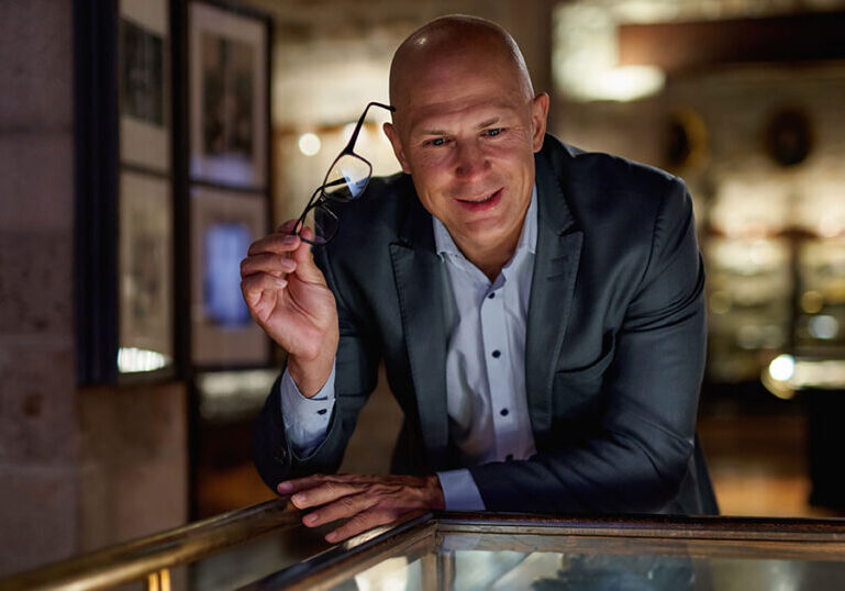 Ultra-high-net-worth individual thoughtfully reviewing a luxury asset collection, symbolizing strategic wealth management and legacy planning