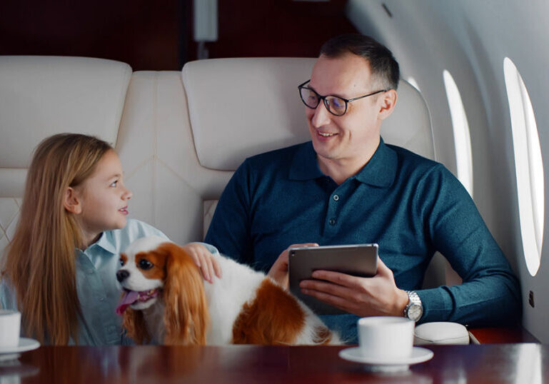 Wealthy father and daughter traveling together on a private jet with their dog, representing the lifestyle and multigenerational wealth management needs of a high-net-worth family