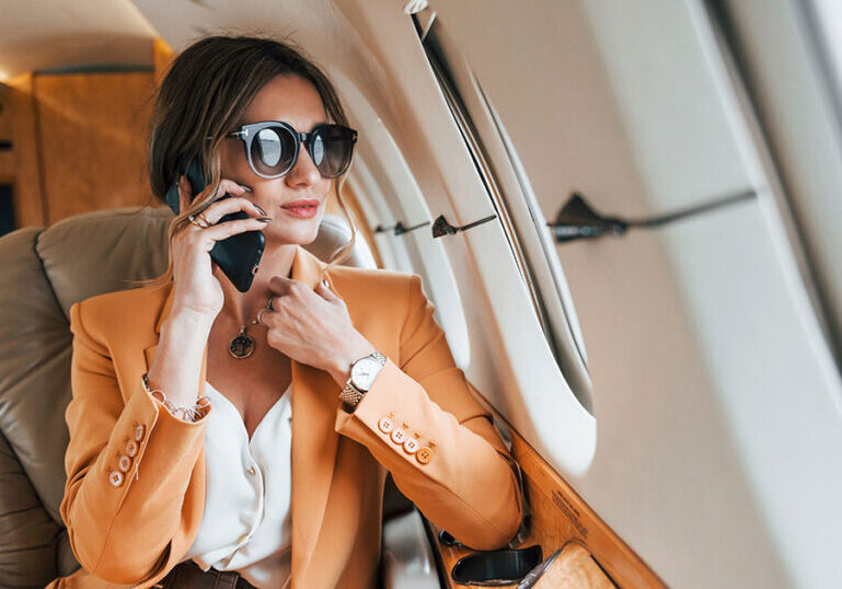 Affluent woman talking on the phone aboard a private jet, representing the lifestyle and complex wealth management needs of an ultra-high-net-worth individual