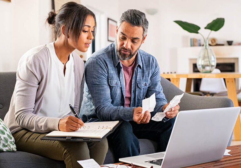 Couple reviewing bills and tracking their monthly budget together on a laptop to avoid common budgeting mistakes and stay aligned with their financial goals.