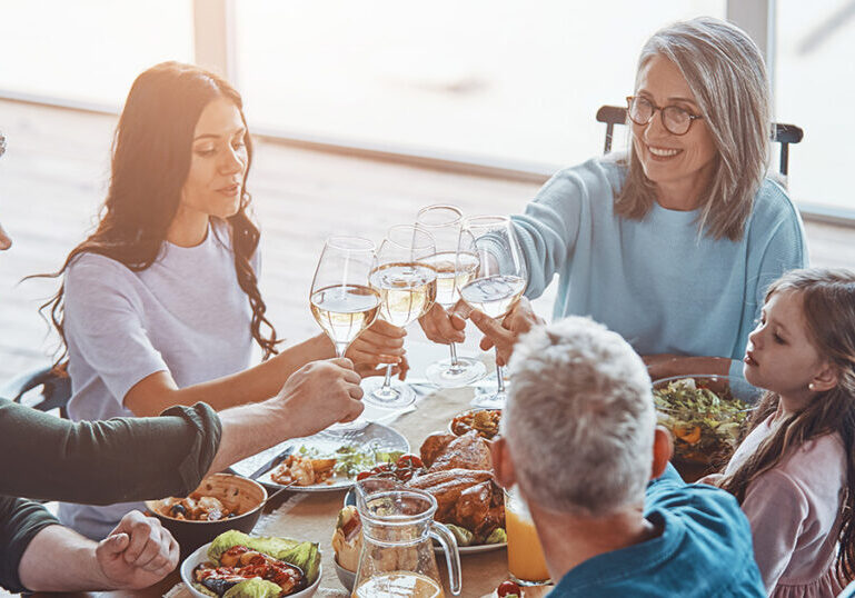Multigenerational family toasting with wine glasses at a holiday dinner table, representing the integrated guidance family office advisory services provide to help preserve and transfer wealth across generations