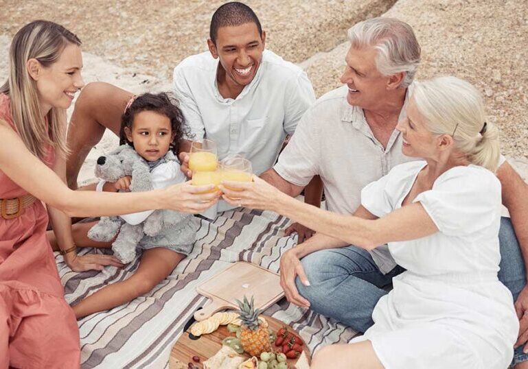 Multigenerational family sharing a beach picnic and toasting together, symbolizing how thoughtful family office structures support wealth, governance and harmony across generations