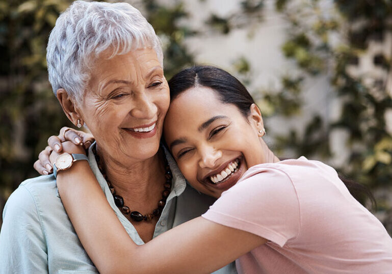 Adult child hugging an older parent outdoors, symbolizing family legacy, multigenerational planning and the impact of 2025 estate tax exemption rules on future inheritances