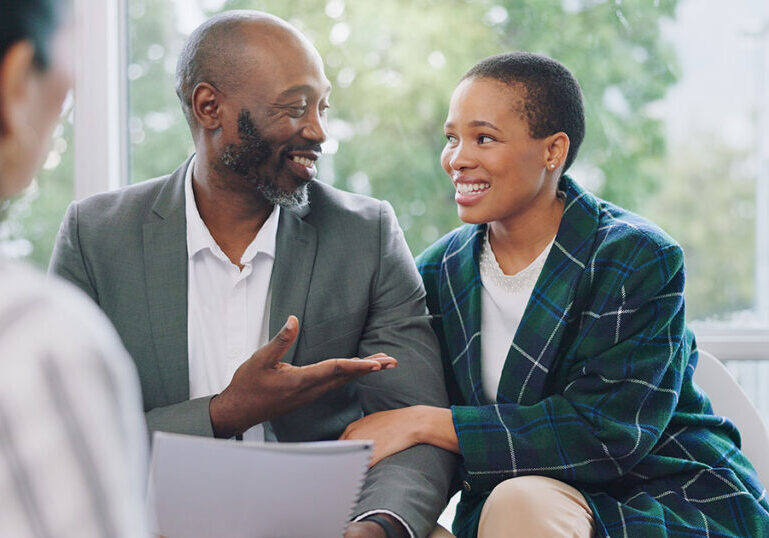 Smiling couple meeting with a financial advisor to discuss setting up a private foundation and long-term charitable giving strategy