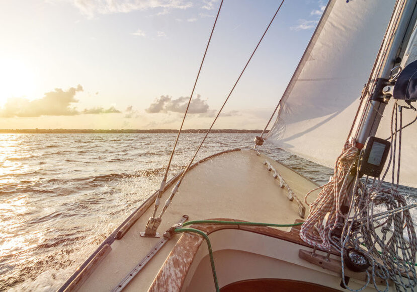 Sailing boat sailing fast into the beautiful sunset during choppy sea