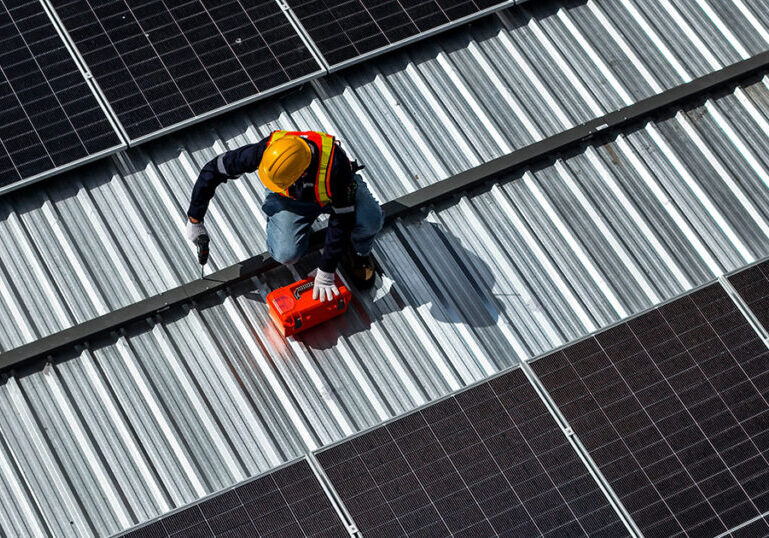 Worker installs solar panels on rooftop