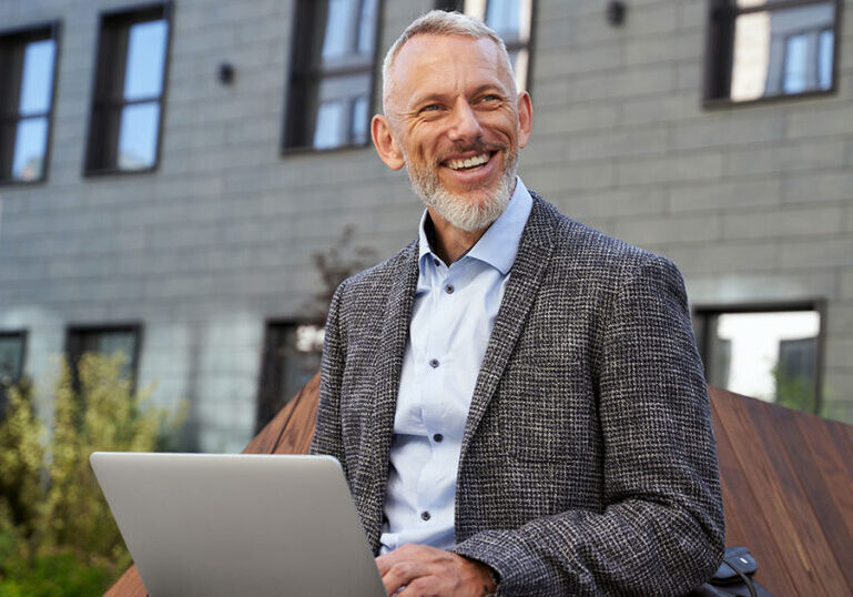 Smiling mature professional working on laptop outdoors